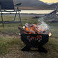 Fire pit with burning logs near a lake and mountains at sunset.